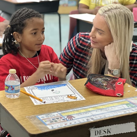 student at desk with teacher