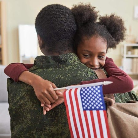 iStock-1477181213 military parent hugging child holding American flag